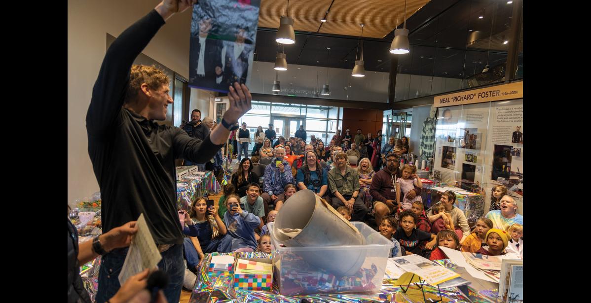 Photo by Anna Lionas TIME CAPSULE OPENING—Joe Fullwood holds up a poster of the New Kids on the Block for the crowd gathered in the Richard Foster Building to watch the opening of the 1990 Summer Reading Program time capsule.