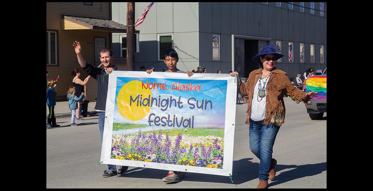 Photo by Julia Lerner MIDNIGHT SUN— Making a nearly 24-hour appearance was the midnight sun, rewarding Midnight Sun Festival organizers Drew McCann, left, and Briday Green, right, with perfect weather for Saturday’s activities, kicking off with a parade. Also pictured is Brandon Rose.