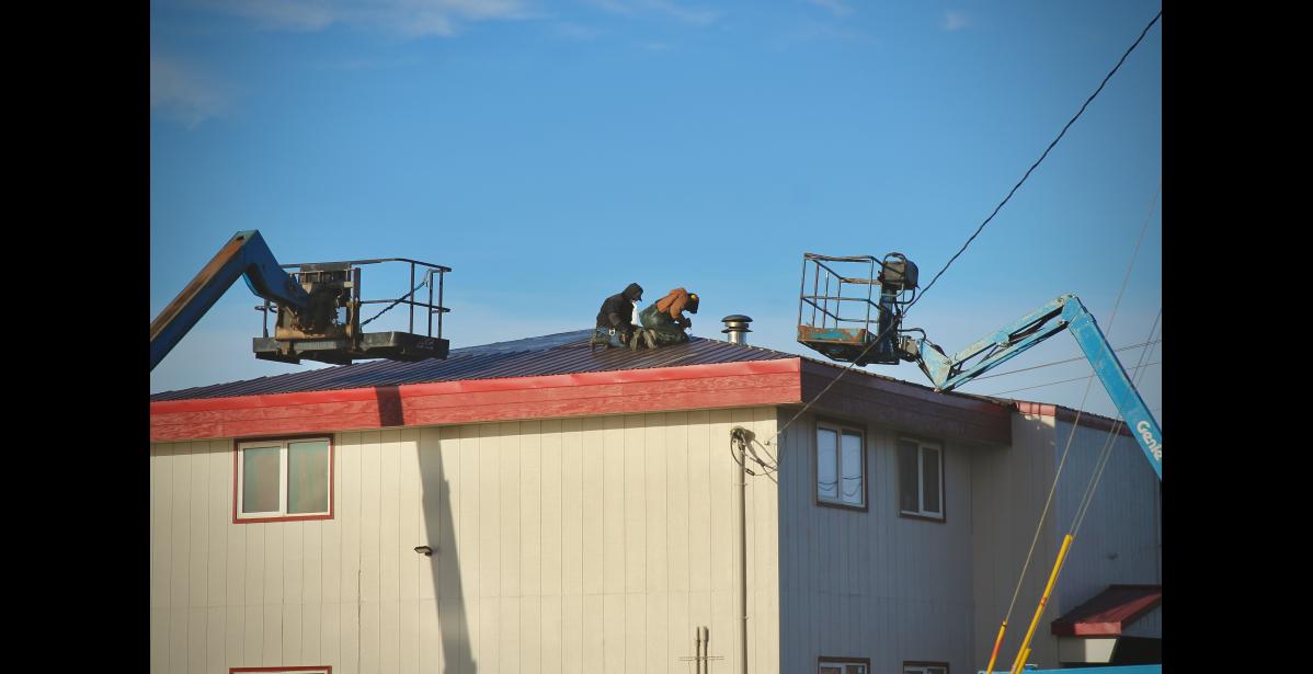 Photo by Jenni Monet Two men in Nome secure sheets of metal to a roof in Nome on Friday. The National Weather Service has issued a high wind warning from 4 a.m. Sunday through Monday morning. Winds are expected to gust up to 70 mph.
