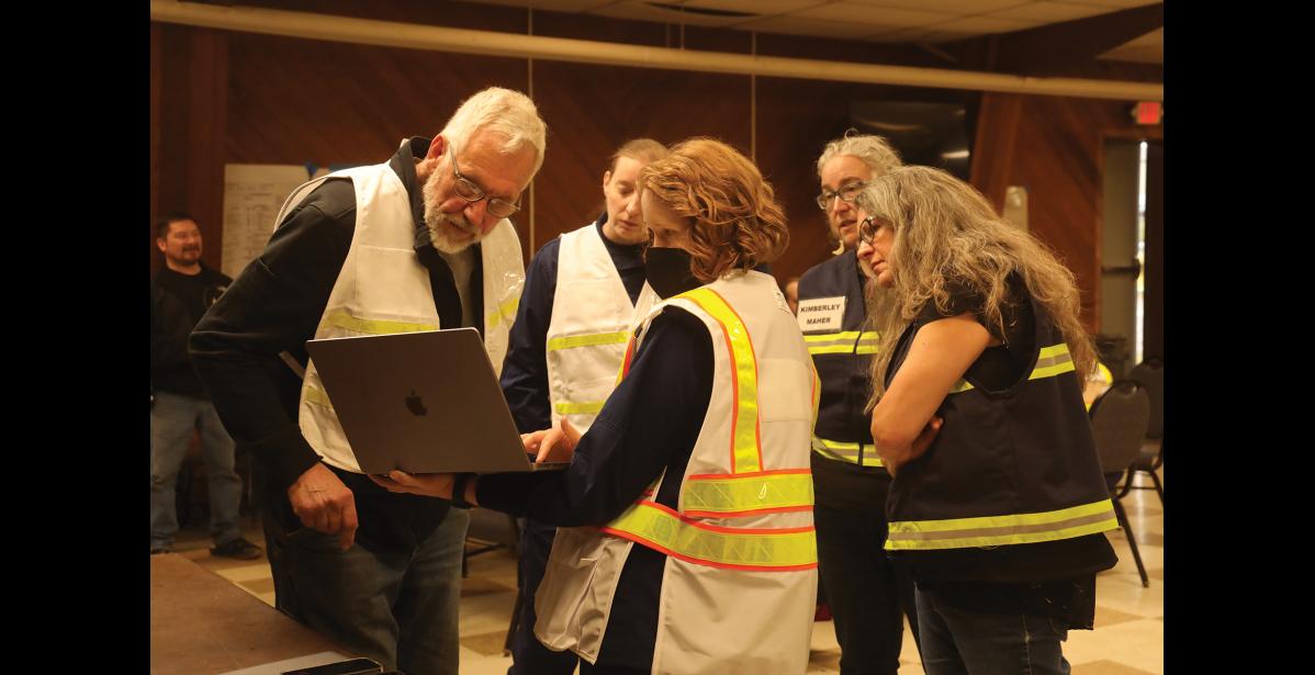 Photo by Laura Robertson DEBRIEF— Charlie Lean, left, and participants in Tuesday’s oil spill response drill discuss the lessons learned.