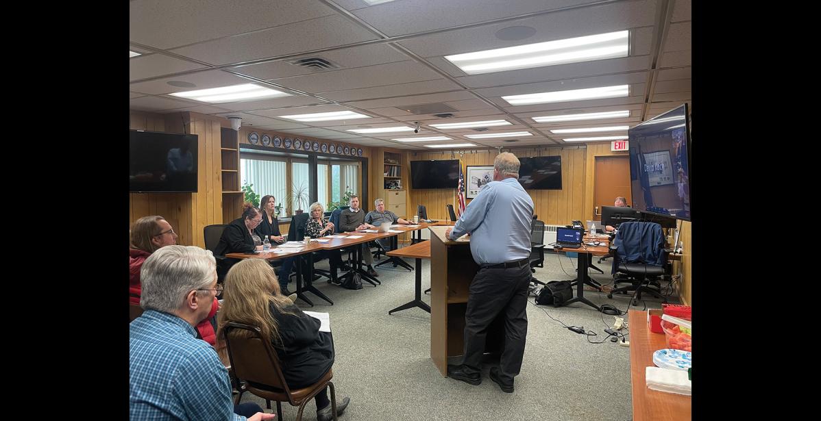 Photo by Megan Gannon TESTIFYING— Mayor John Handeland speaks at the AMCO meeting on Monday. From left to right at the table are Carrie Craig, AMCO’s records and licensing supervisor; Joan Wilson, AMCO’s director; Diane Thompson, ABC board member; Dana Walukiewicz, chair of the ABC board; Doug Moore, ABC board member.