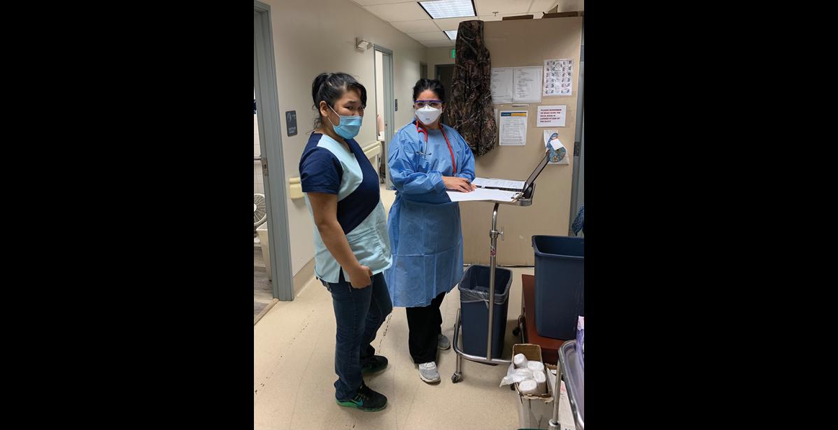 Photo by Mark Hayward ON THE FRONT LINES— Dr. Cristina Peñon, right, consults with CHA-II Camille Katcheak, left, before donning full personal protective equipment to interview a positive COVID-19 patient in Stebbins.
