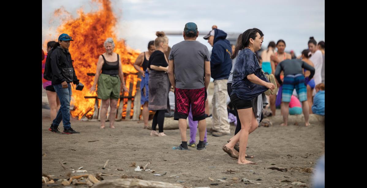 Photo by Sarah Manriquez Participants warm up by the bonfire after braving the icy waters of the Bering Sea during the annual Polar Bear Plunge on Saturday, June 21, 2025.