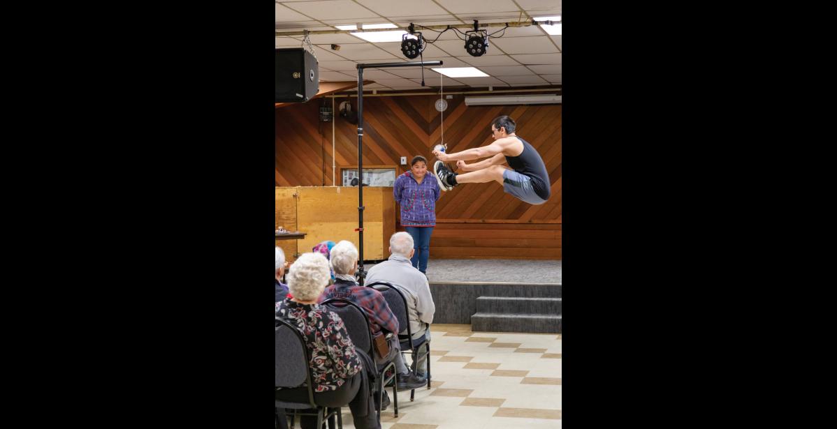 Photo by Sarah Manriquez FANCY FOOTWORK— NYO athlete Parker Kenick performs the Two-Foot high kick during a cultural demonstration for Westerdam cruise passengers at the Nome Mini-Convention Center on Thursday, June 19, 2025. Kenick, a 20-year-old from Nome, won the 2024 World Eskimo-Indian Olympics event with a jump of 8 feet 2 inches. Former Miss WEIO and longtime judge Marjorie Tahbone observes from the stage, just as she would during competition. Traditionally, the Two-Foot High Kick signaled a successful hunt, calling the comm