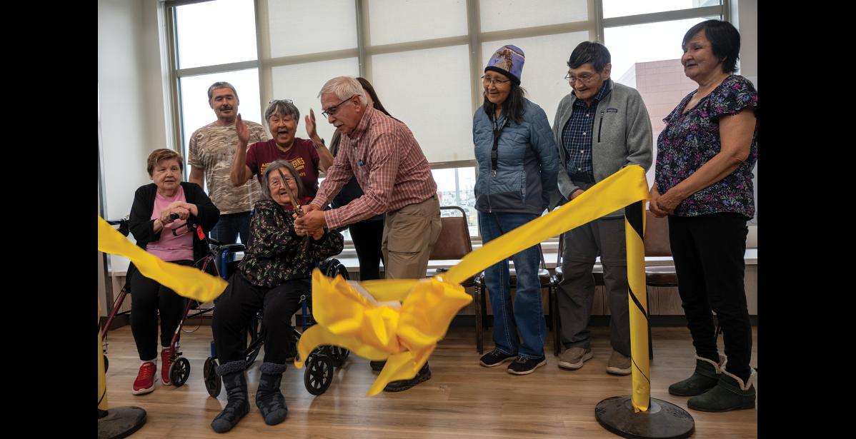 RIBBON CUTTING— Norton Sound Health Corporation board members Berda Willson of Native Village of Council (seated), Charlie Brown of Chinik Eskimo Community, Matilda Hardy of Native Village of Shaktoolik, Wilma Amaktoolik of Village of Solomon, Tony Haugen board chair of Native Village of Unalakleet, Rosemary Otton of Native Village of Koyuk, Frederick Murray of Native Village of Elim, and Joanne Oxereok of Native Village of Wales celebrate as Quyanna Care Center resident Sarah Kakaruk cuts the ceremonious ribbon to QCC's expanded facility, on Thursday, September 17. Photo by Ariana Crockett O'Harra