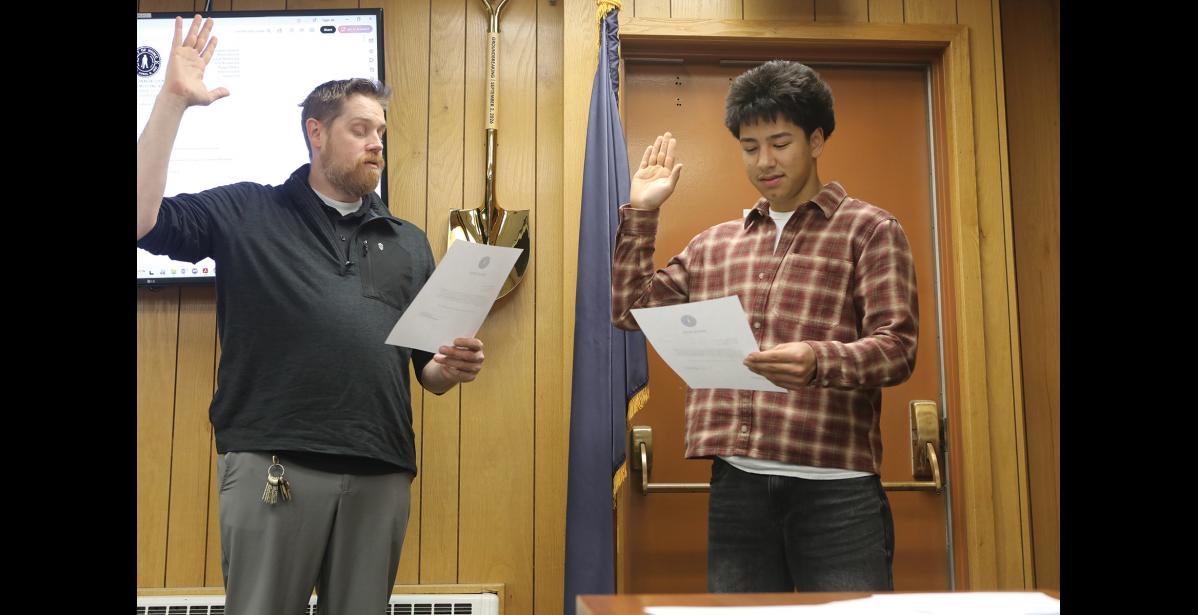 City Clerk Dan Grimmer administers the oath of office to student representative Lane Schuerch, during the Sept. 28 council meeting. Photo by Diana Haecker