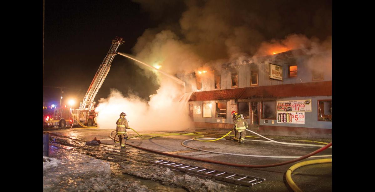 Photo by James Mason FIRE AT THE POLARIS— Nome Volunteer Fire Dept. fire fighter Kevin Knowlton walks by the burning Polaris building in the early morning of Oct. 31. Later that afternoon, one person’s body was recovered from the burned rubble of the back building. The identification is pending