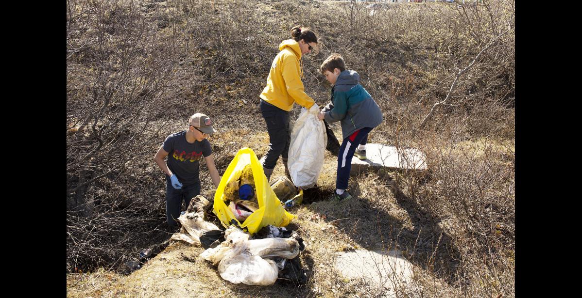 Photo by James Mason SPRING CLEANUP— Reese Bahnke, left, pulls trash out of a ditch near the Nome-Teller Highway while Hayden Leeper helps Nancy Bahnke fill a trash bag Saturday during the annual Nome spring cleanup.