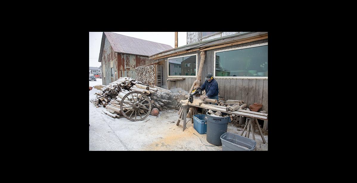 Photo by James Mason TO NOME BY CANOE – Jerry Pushcar works on driftwood he has gathered, cutting it down to size for his woodpile. Pushcar made his home in Nome after having arrived here 42 years ago by canoe.