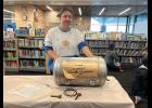 Photo by Diana Haecker TIME CAPSULE— Library Assistant Janet Steppe holds the 1990 Time Capsule, which will be opened on July 17 at the Kegoayah Kozga Library.